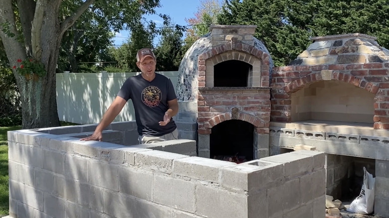 A man standing behind a DIY cinderblock project.