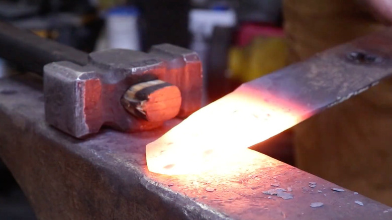 Forging a red hot lawn mower blade into shape