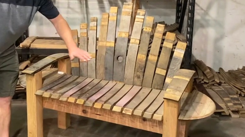 A hand showing a bench made from wine barrels.