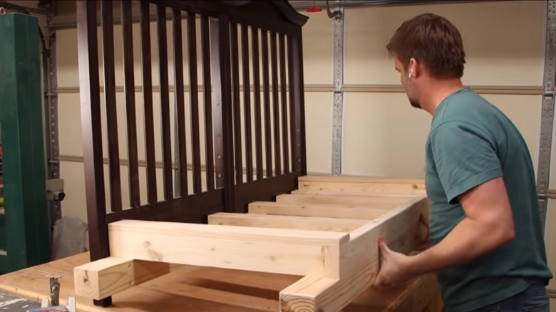 person DIYing an old crib into a porch swing by adding wood seat box