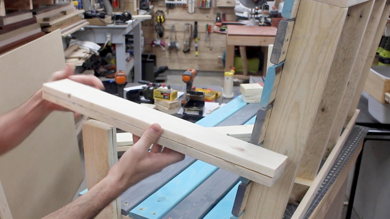 person holding wood for building pallet patio swing chair