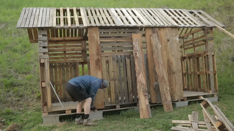Person working on partially constructed pallet wood cabin