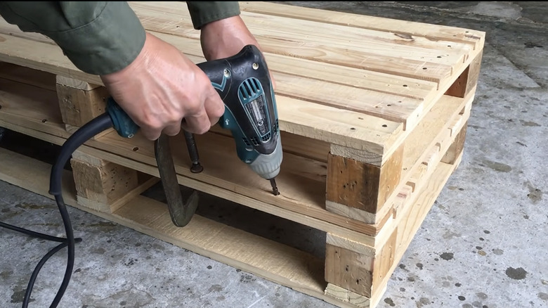 Screwing wood pallets together to make the base of the convertible bench