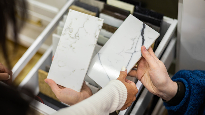 Close-up of hands of two women browsing marble samples at a store
