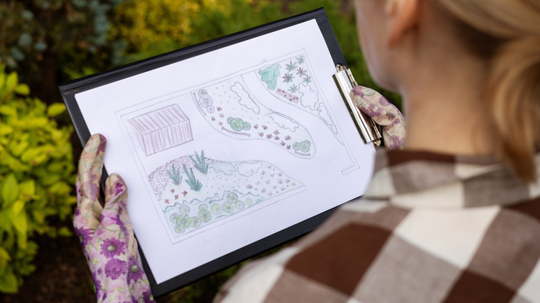 A woman looks at a tablet with an image of her backyard blueprints