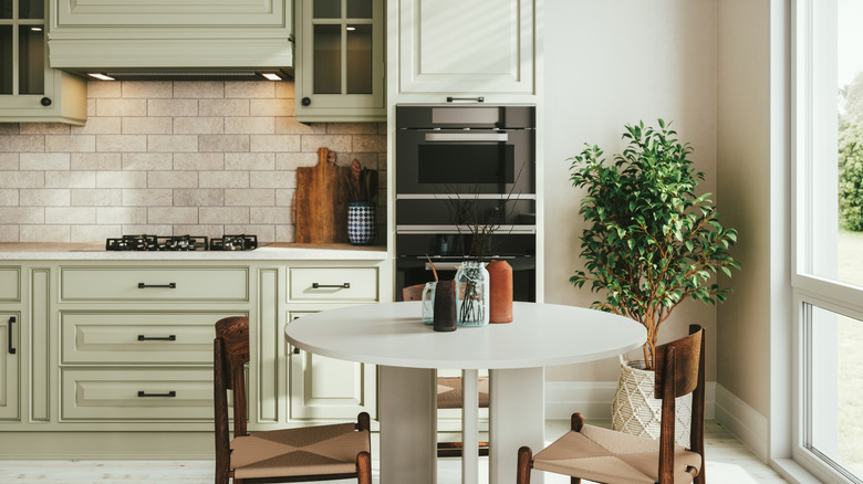 Welcoming kitchen with expensive-looking gray-green cabinets and a small white table