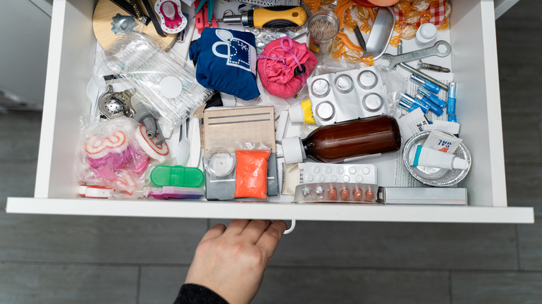 Someone pulling open a junk drawer full of random items
