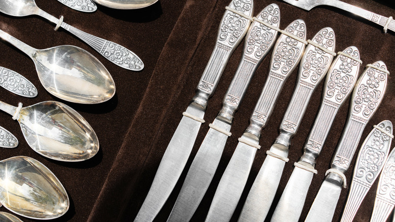 A close-up of vintage silverware arranged neatly on fabric