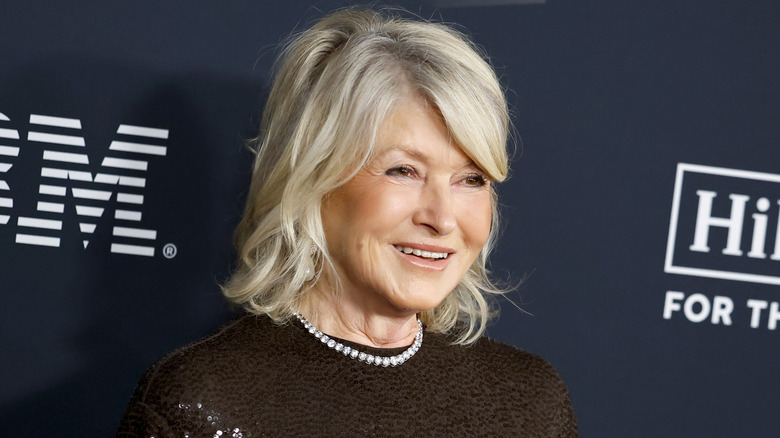 Martha Stewart smiling in front of a navy blue sponsors backdrop at an event
