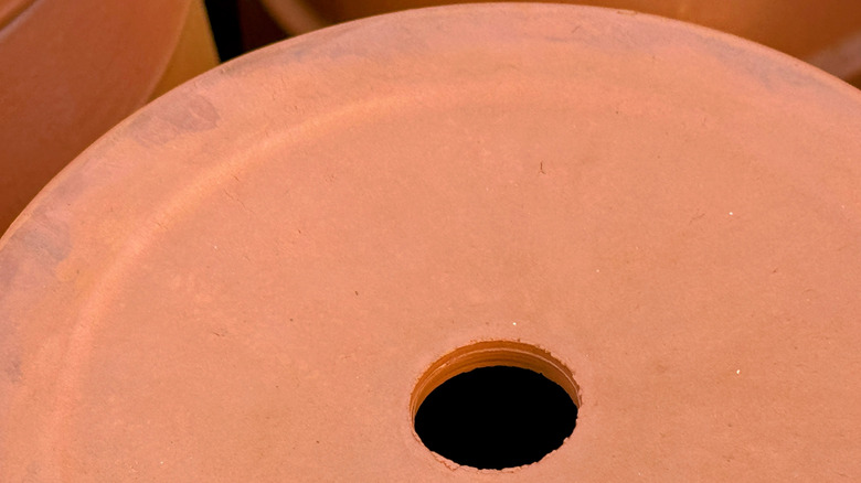 A hole in the bottom of a terra cotta clay pot.