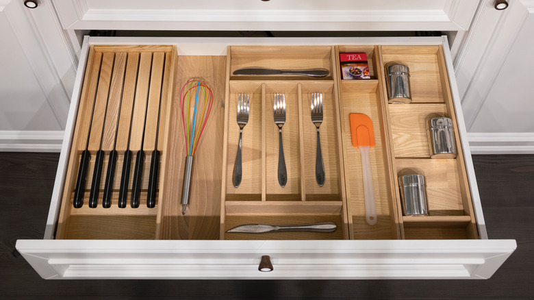 Open kitchen drawer with knives in a wooden holder