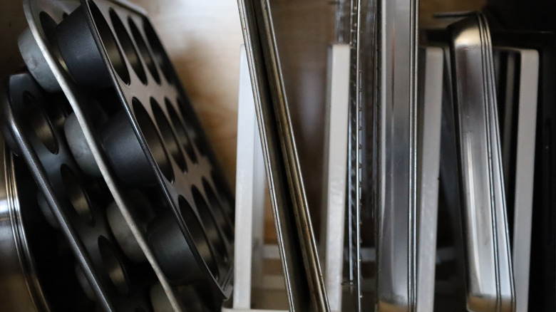 Muffin tins and baking sheets stored vertically with metal dividers