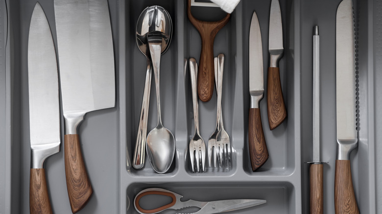 A drawer organizer with a variety of chef's knives inside