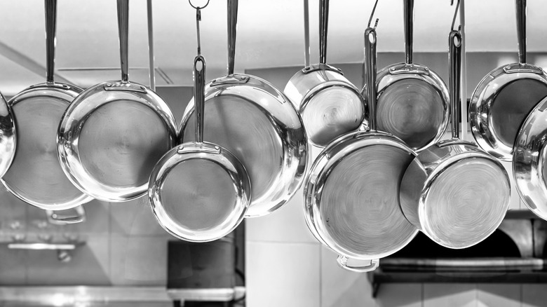 Stainless steel pots hanging from the ceiling by the handles