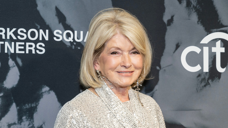 Martha Stewart smiling at the camera against a dark blue background