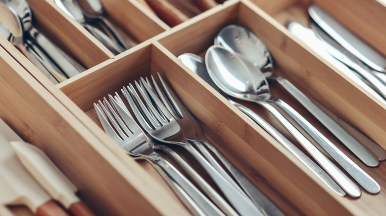 Closeup of a wooden utensil divider with forks, knives, and spoons