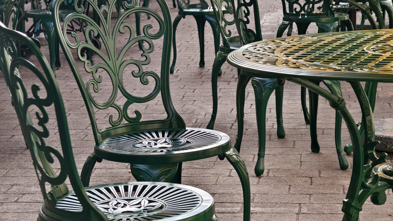 An outdoor dining space featuring painted wrought iron furniture.