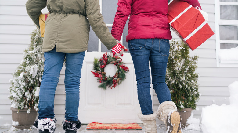 women entering Christmas decorated porch