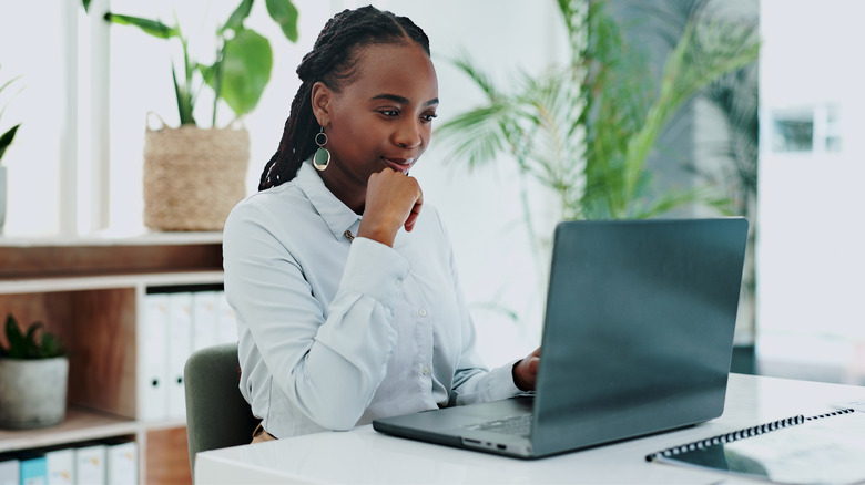 An African American woman homeowner accesses information on a laptop.