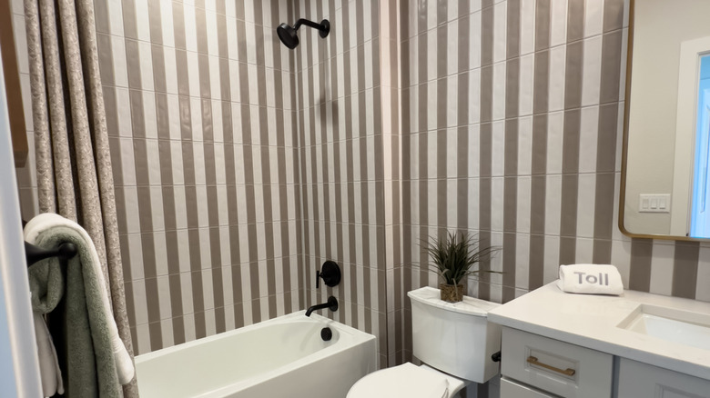 A bathroom with taupe and white striped tiles on walls