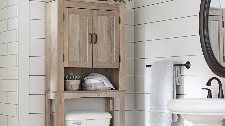 Bathroom with over the toilet storage unit with doors