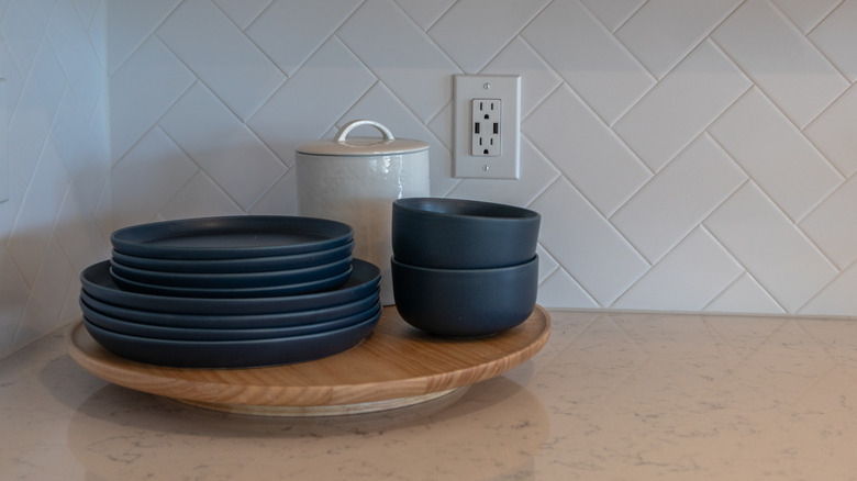 Lazy susan on kitchen countertop with plates and bowls stacked on top.