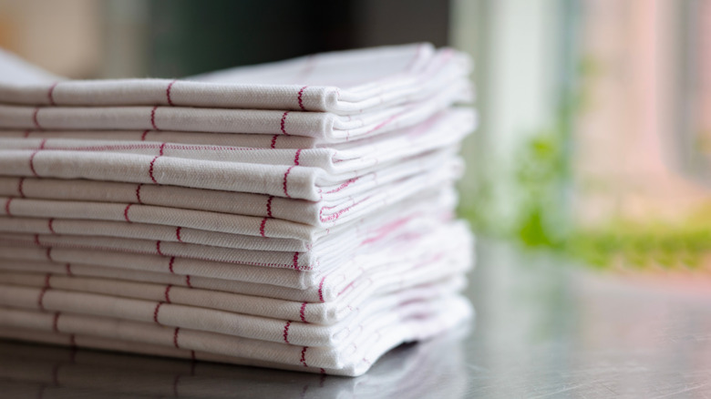A stack of clean kitchen towels sits on a counter.