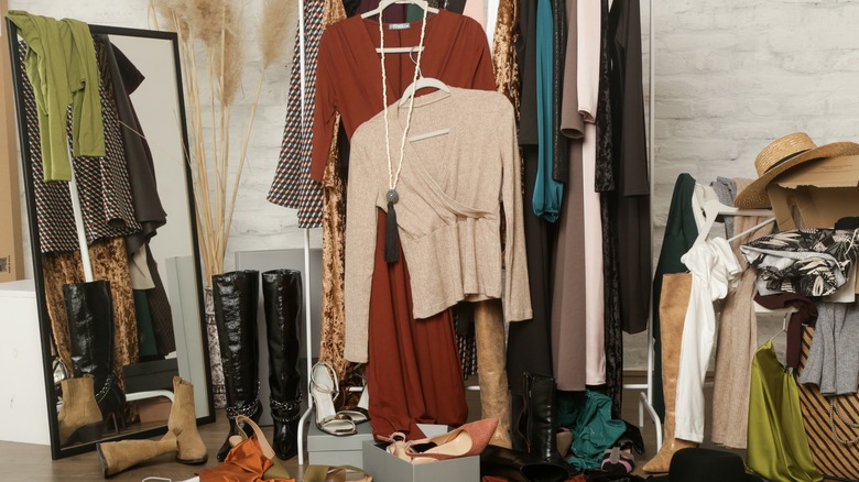 Clothes, shoes, and other belongings are strewn about a messy, crowded closet.