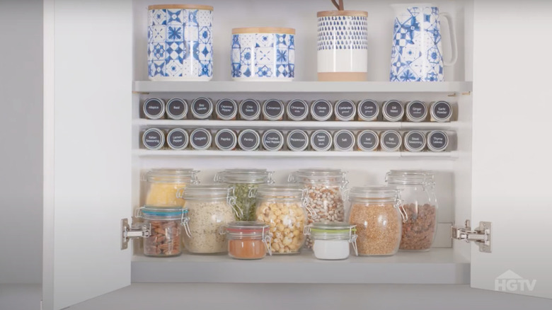 Person holding a spice while reaching into a cabinet