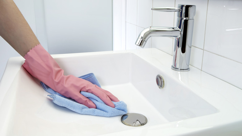 gloved hand wiping bathroom sink