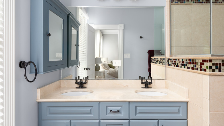 A boxy blue medicine cabinet blocking a part of the mirror above a bathroom counter