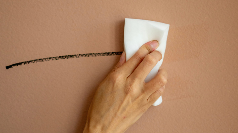 Hand cleaning mark off wall with magic eraser