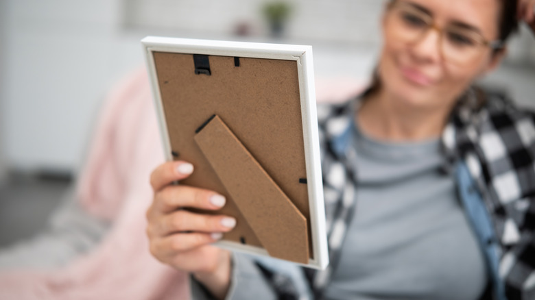 A person holding a simple, white photo frame