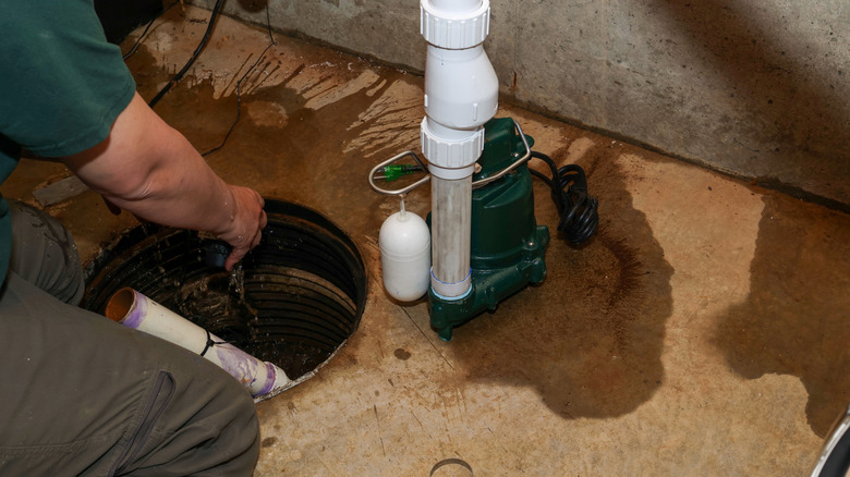 man fixing sump pump drainage in basement
