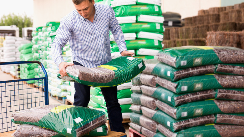 A man loading bags of soil onto a flatbed cart at a store