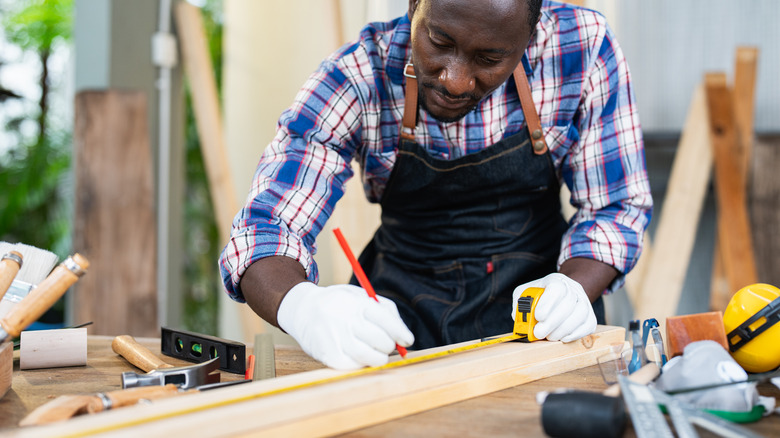 Person marking a board to make cuts