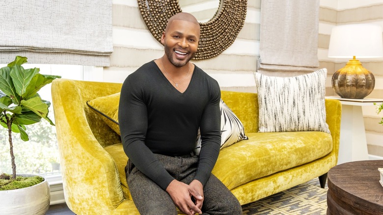 Michel Smith Boyd smiling and sitting on a yellow couch