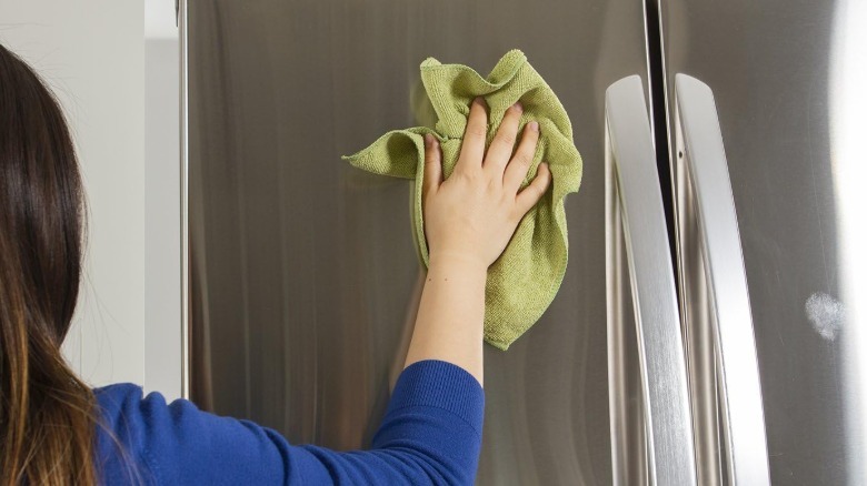 A person uses a red bamboo fiber towel to wipe down a wooden kitchen countertop.