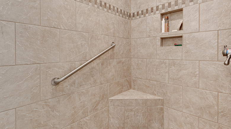 tiled shower with grab bar in the corner