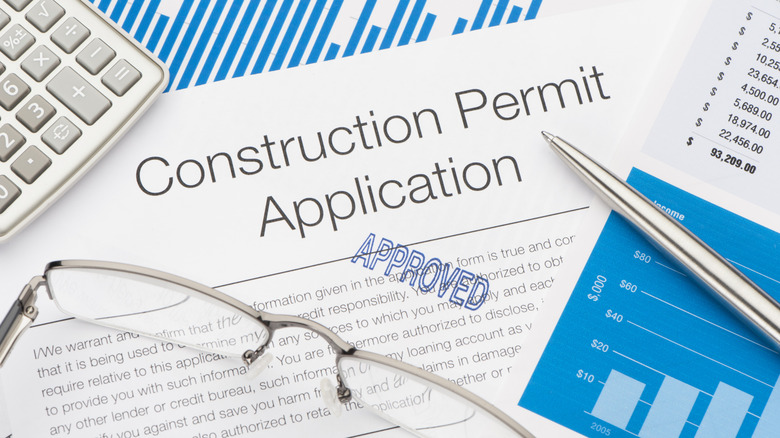 Approved Construction Permit Application with pen and calculator