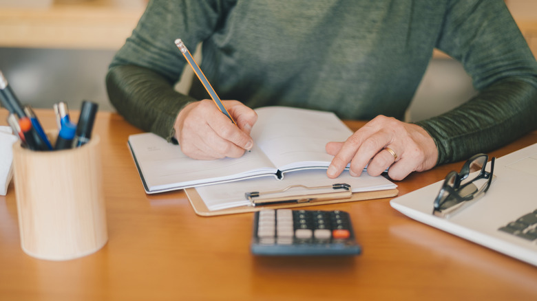 person making a budget with notebook and calculator