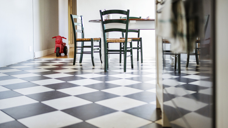 A kitchen with a black and white tile floor and wooden dining table