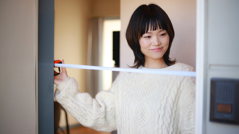 A woman measures the width of a door