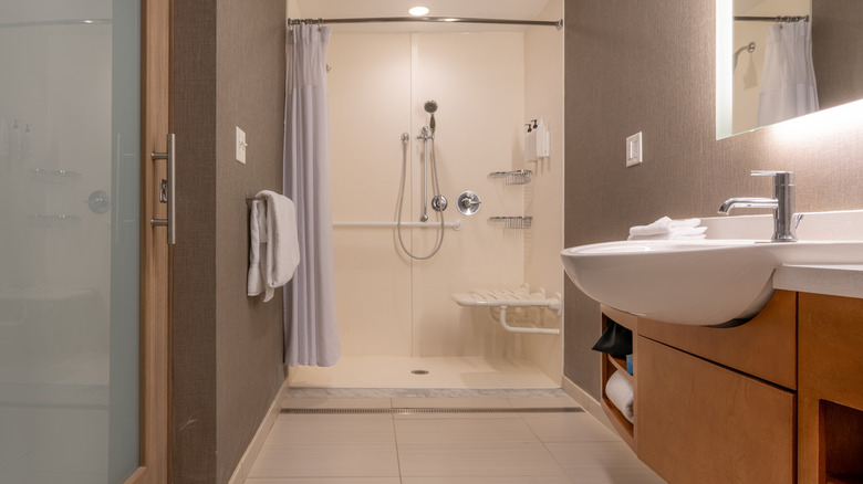 A basic bathroom with a sink in the foreground and a curbless shower in the background.