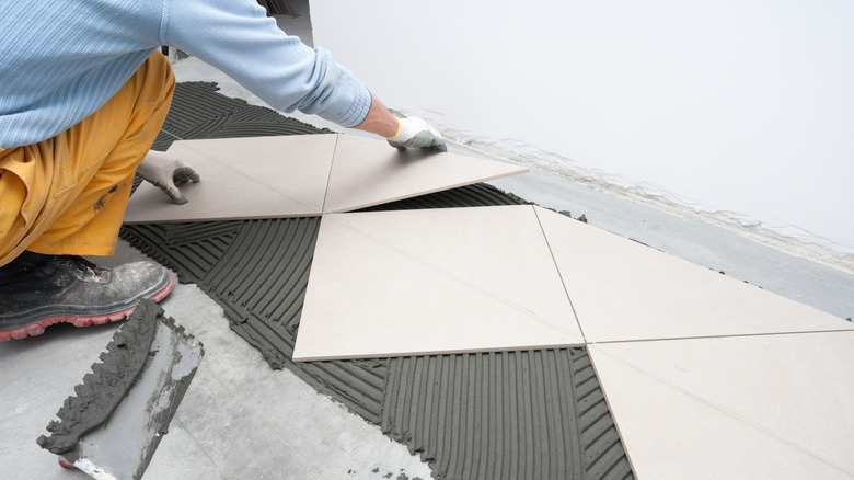 A person installs tiles for his bathroom floor