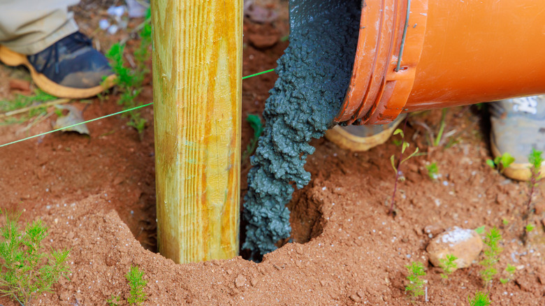 Pouring concrete into a fence post hole