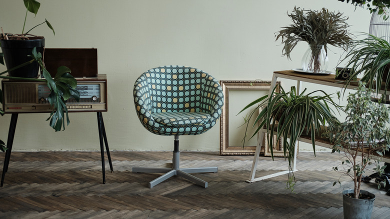 A retro style chair, retro furniture, and houseplants in a living room.