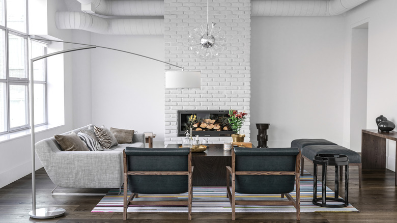 An all-white living room with a painted brick fireplace
