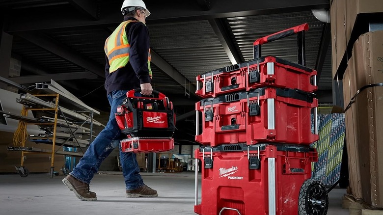 A worker carrying a Milwaukee Packout toolbox