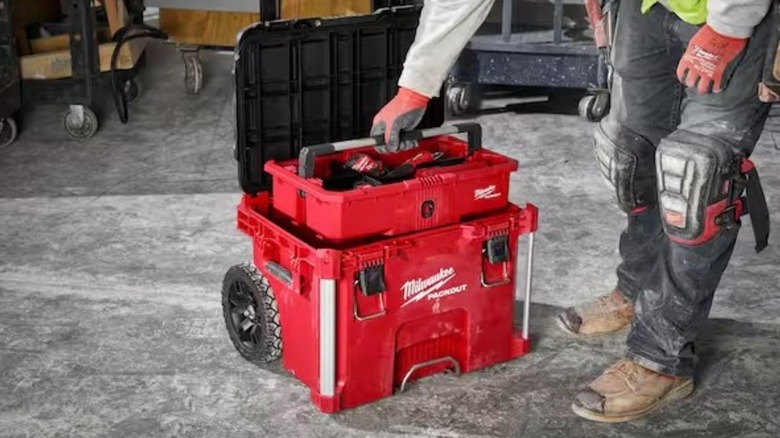 Man lifting the tray out of the rolling toolbox filled with tools